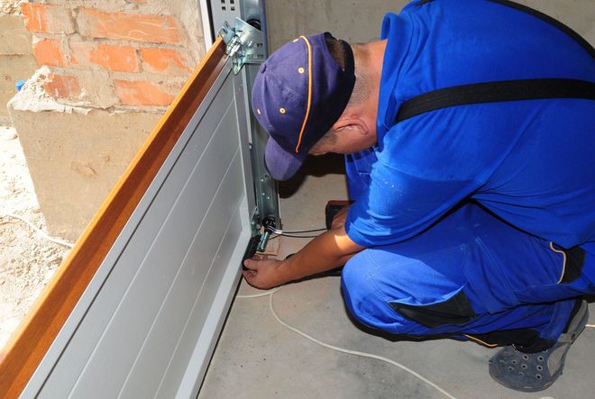 Man in blue coveralls installing garage door.