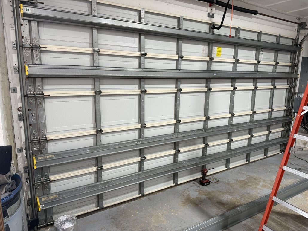 Closed gray industrial garage door with horizontal panels in a warehouse or garage interior.