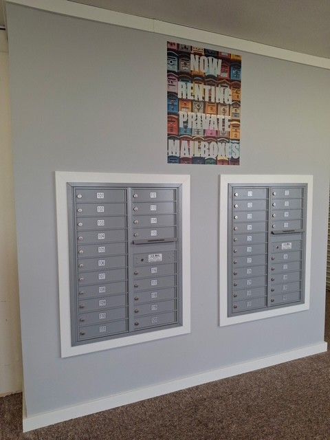 Two gray mailboxes recessed into a gray wall.