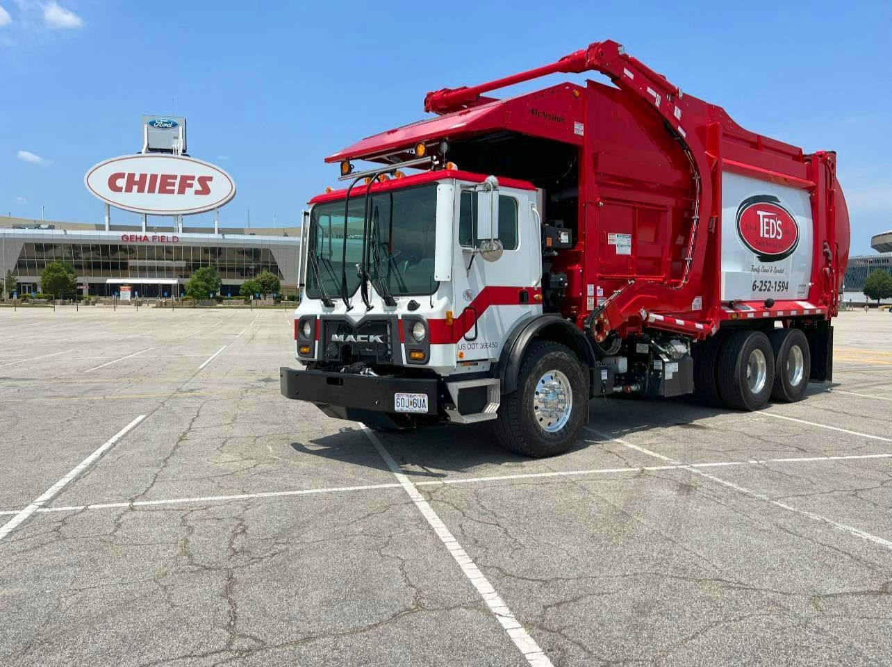 Red and white Chiefs garbage truck parked in a stadium lot with a Chiefs sign in the background