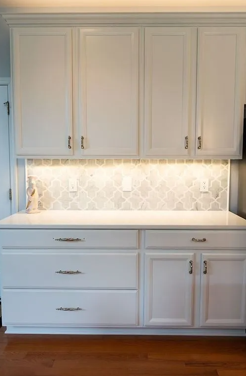 A kitchen with white cabinets and drawers and a counter top.
