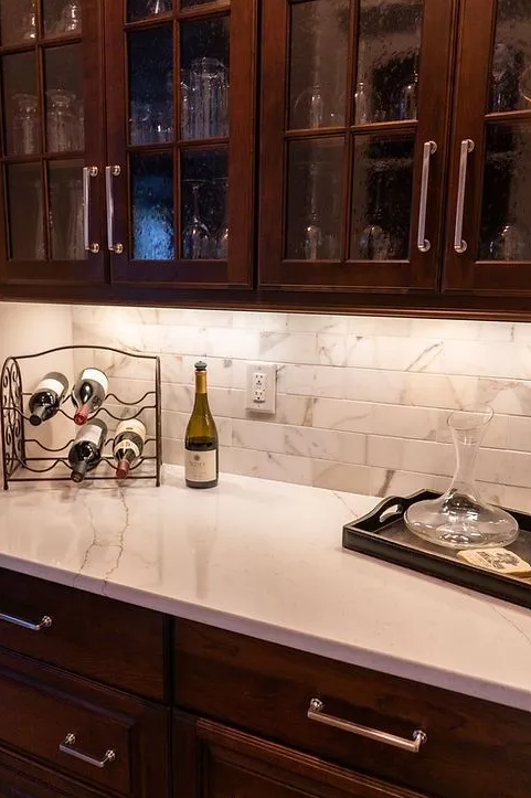 A bottle of wine is sitting on a counter next to a wine rack.