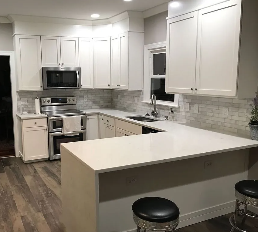 A kitchen with white cabinets , stainless steel appliances , a sink , and a microwave.