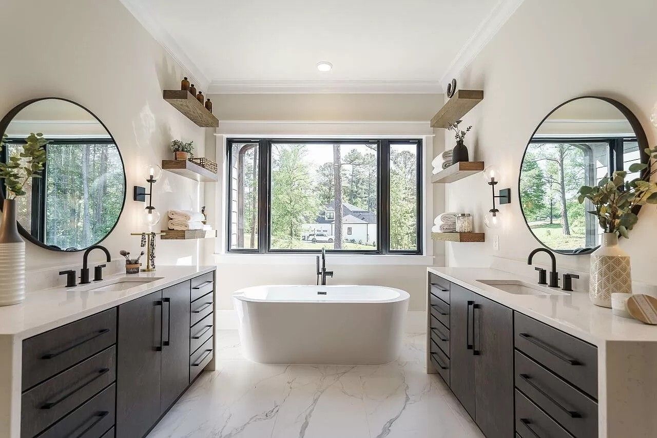 A bathroom with two sinks , two mirrors and a bathtub.