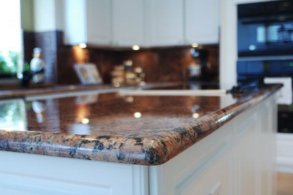 A kitchen with a granite counter top and white cabinets