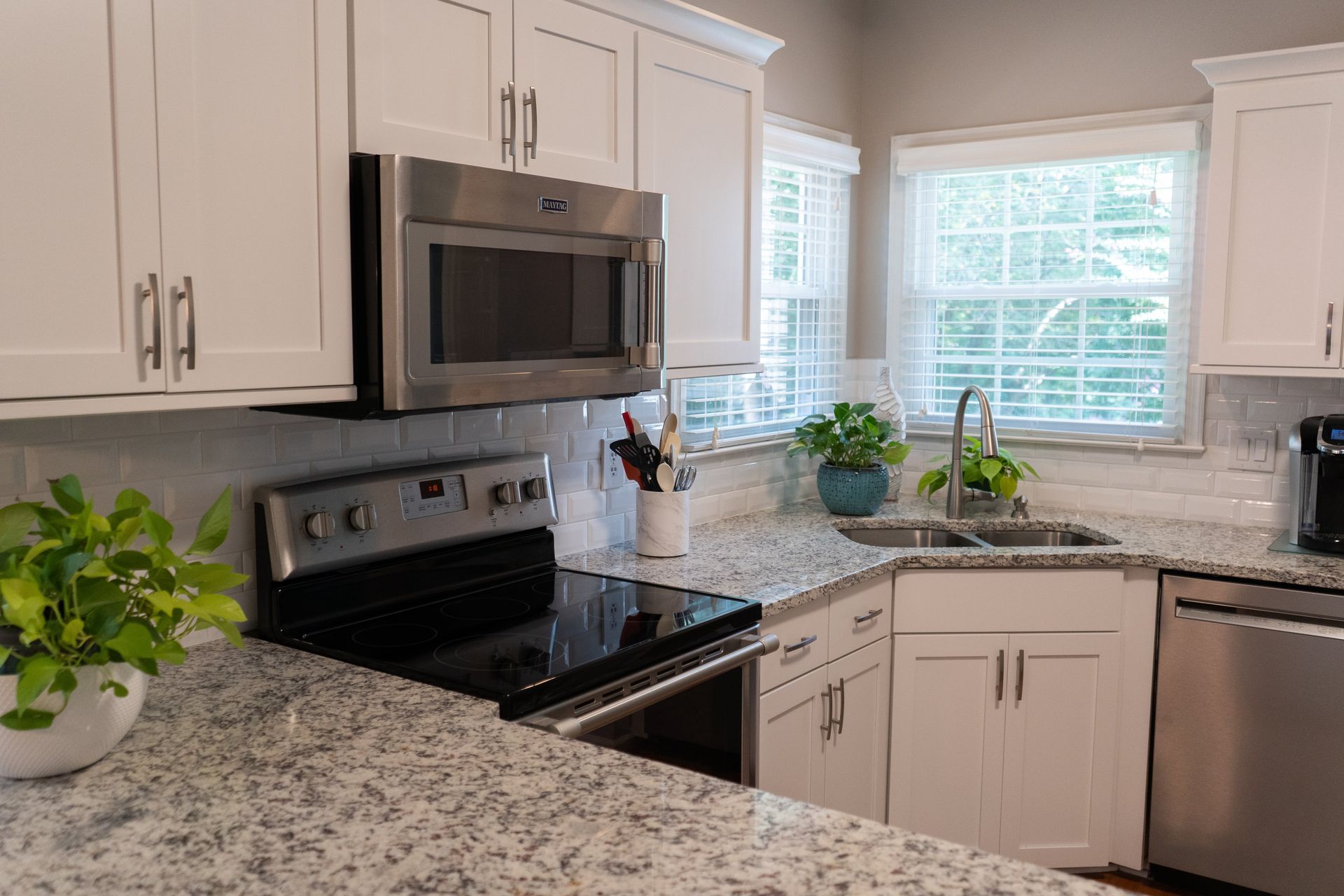 A kitchen with granite counter tops , stainless steel appliances , and white cabinets.