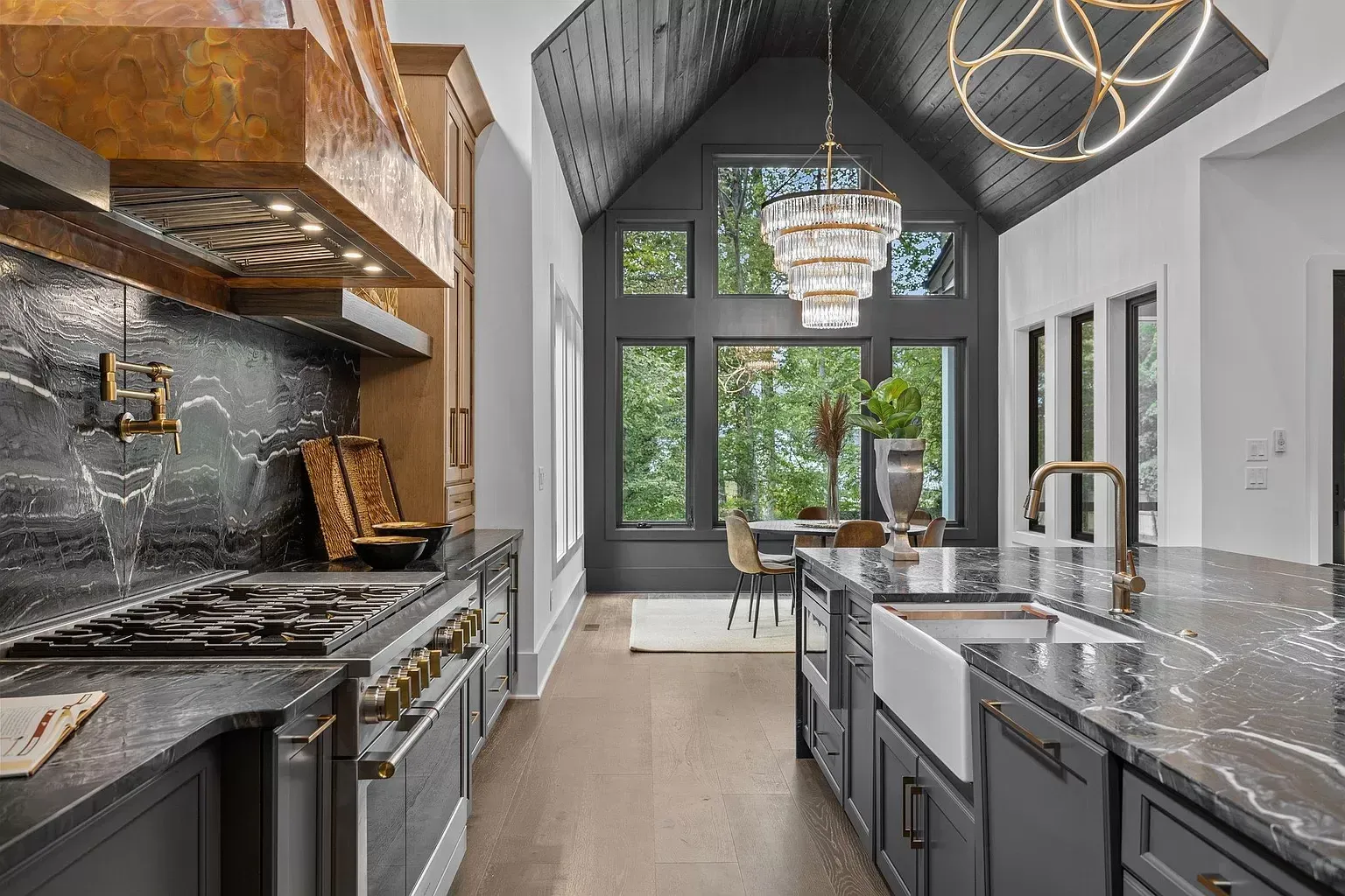 A kitchen with a stove , sink , and a large window.