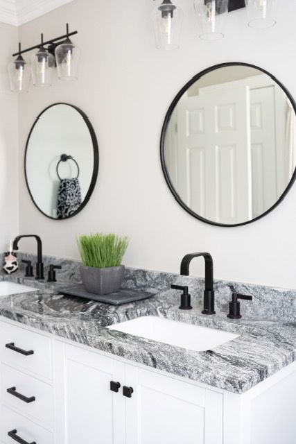 A bathroom with two sinks and two round mirrors.