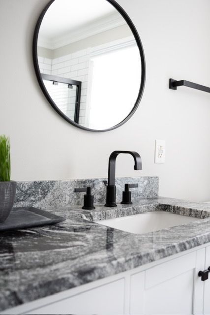A bathroom sink with a round mirror above it