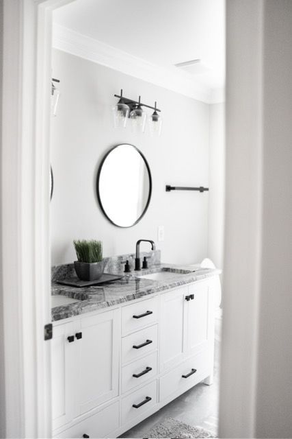 A bathroom with white cabinets , a sink and a mirror.