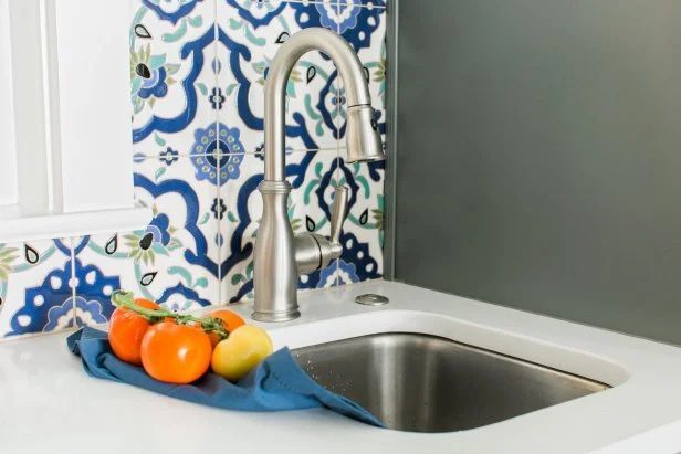 A kitchen sink with a faucet and fruit on the counter.