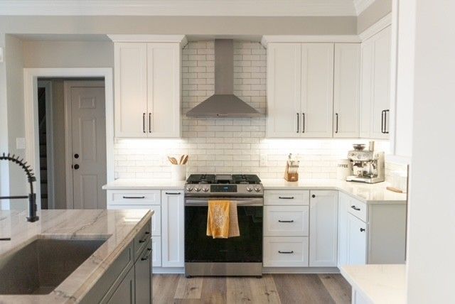 A kitchen with white cabinets , stainless steel appliances , a sink , and a stove.