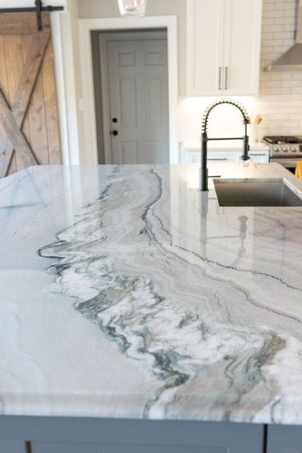 A kitchen with a marble counter top and a sink.