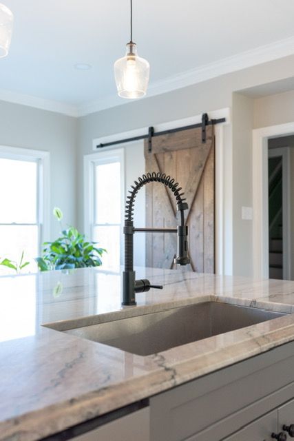 A kitchen sink with a sliding barn door in the background