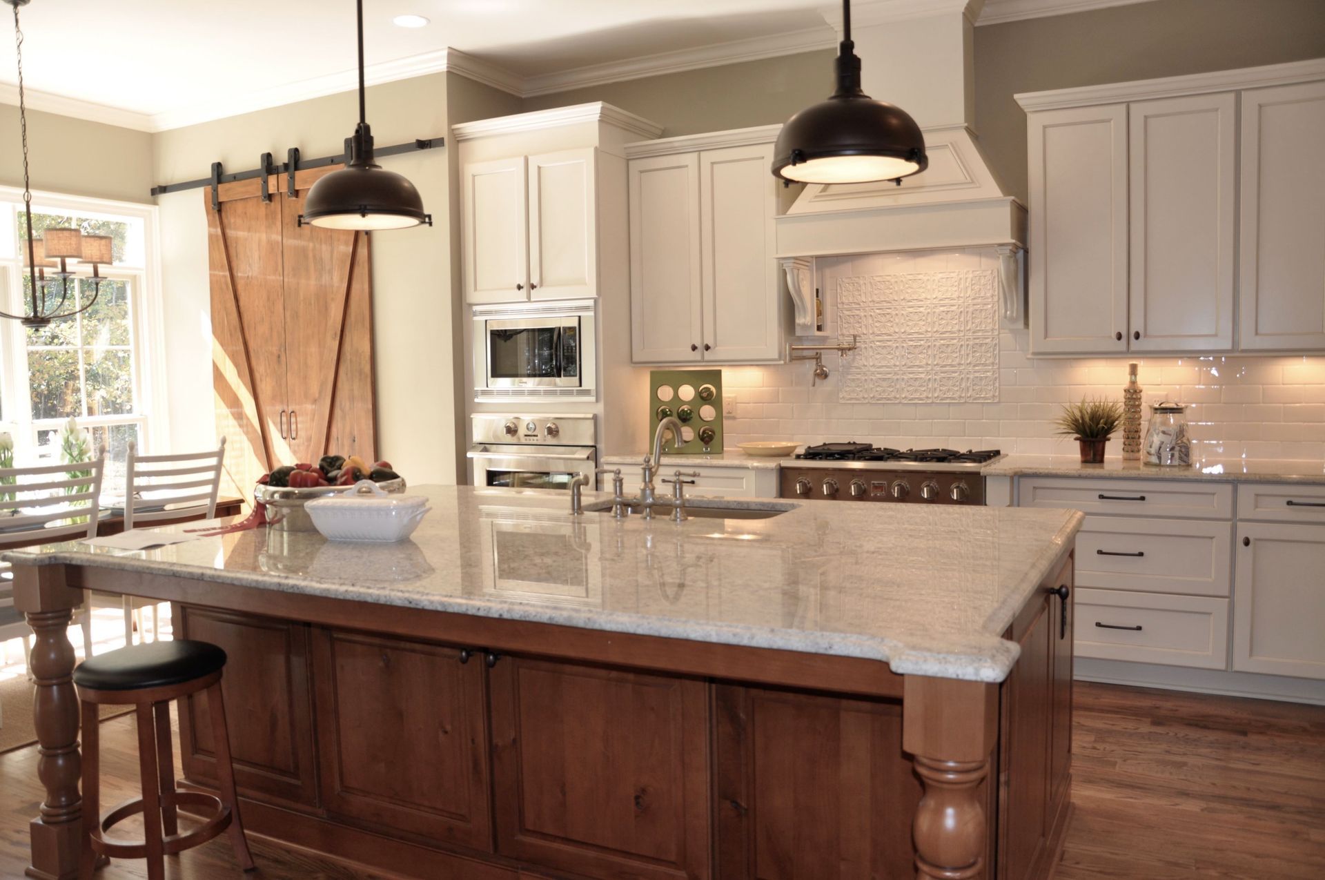 A kitchen with white cabinets , granite counter tops , and a large island.