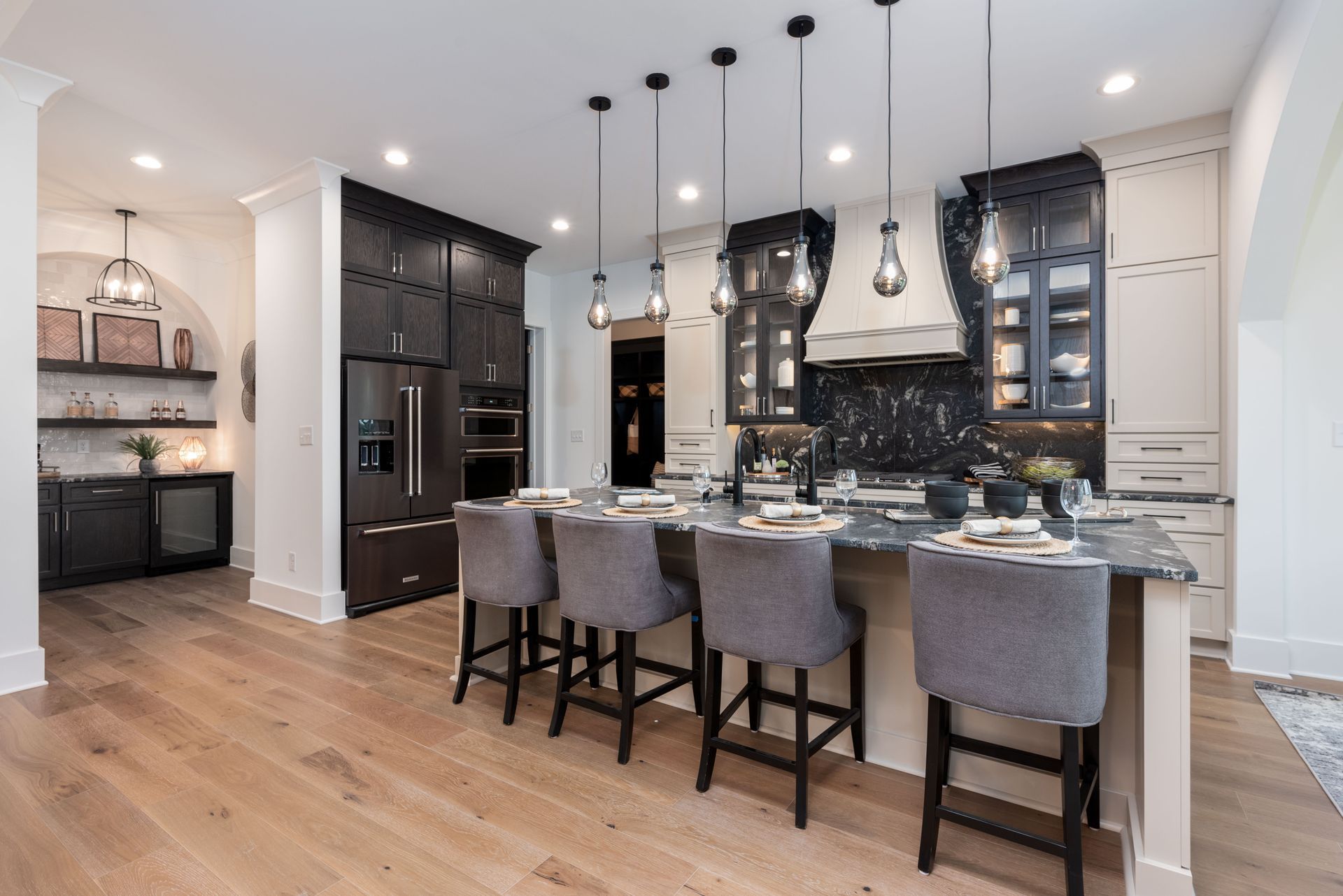 A kitchen with a large island and stools in it.