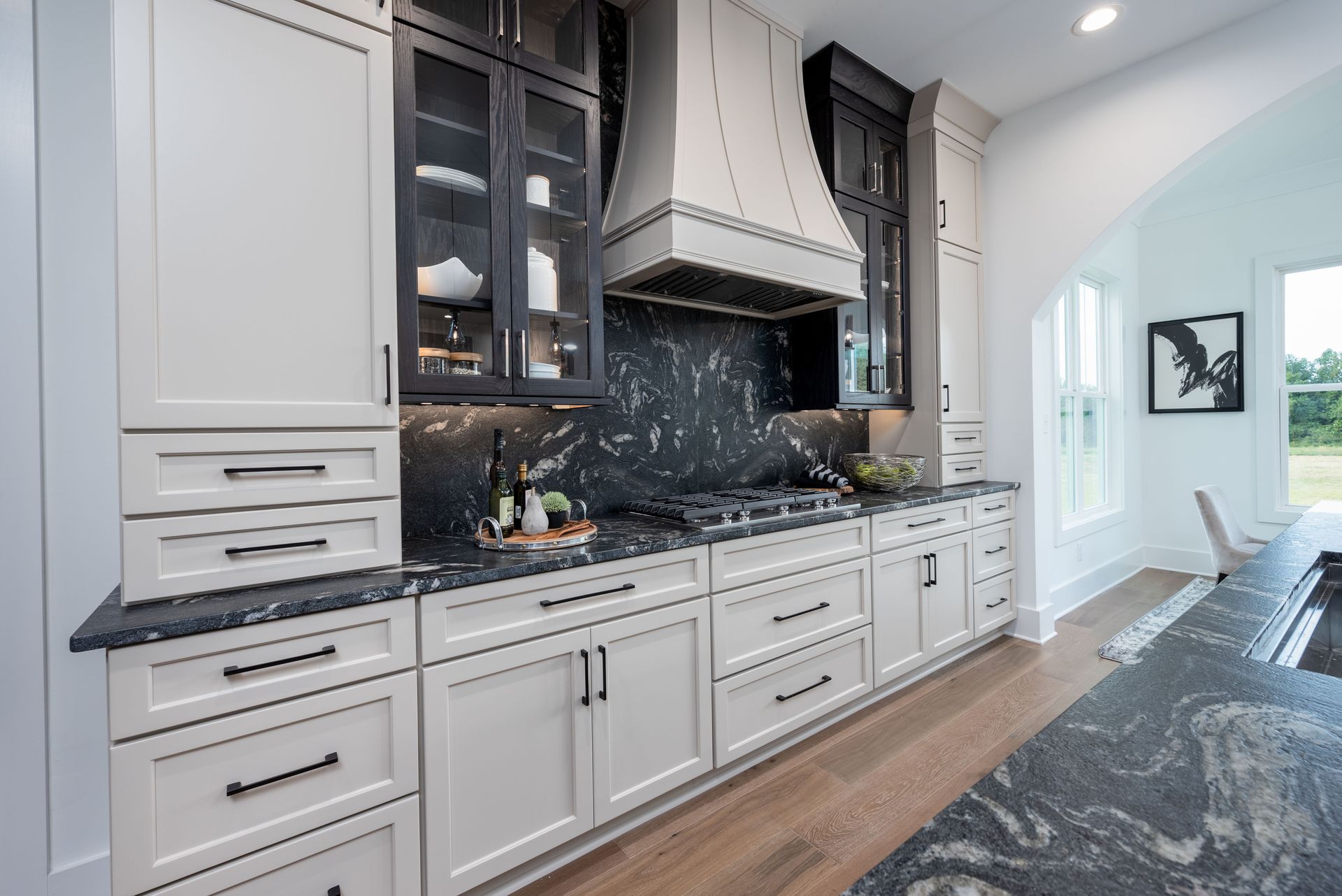 A kitchen with white cabinets and black granite counter tops.