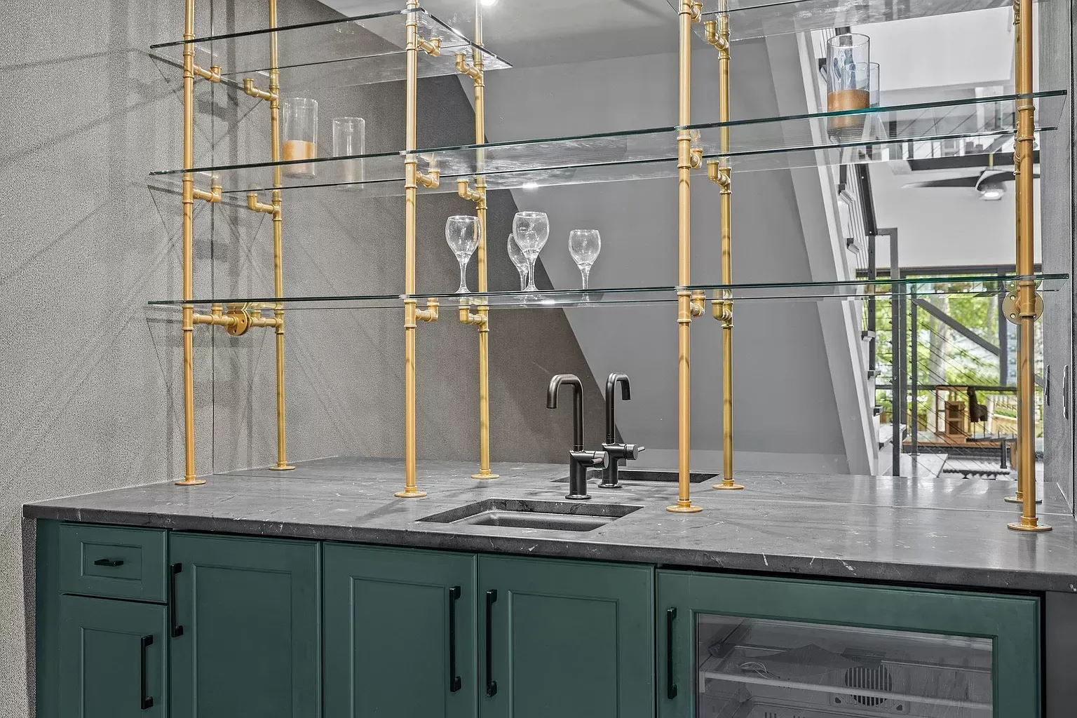 A kitchen with green cabinets , a sink , and a bar.