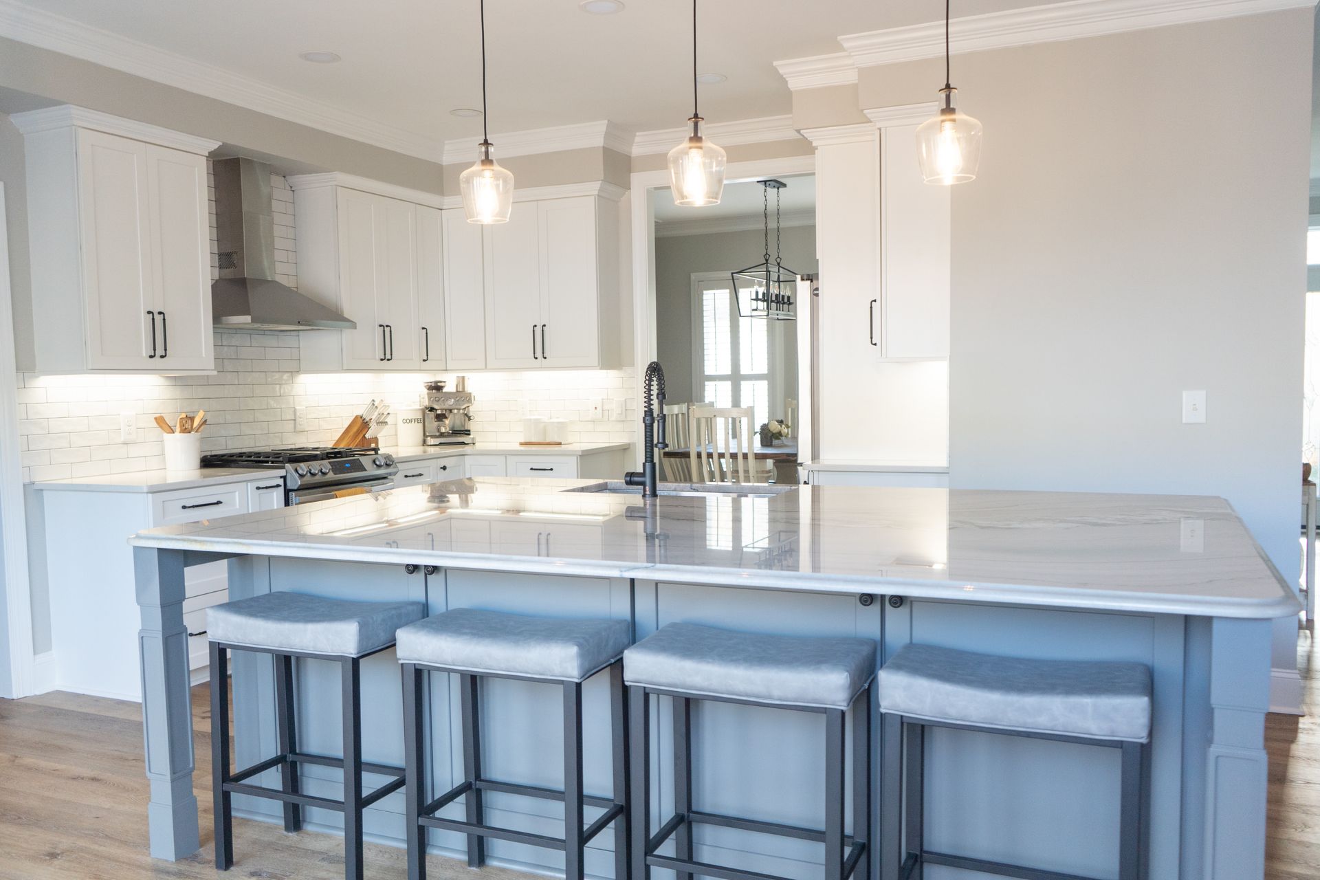 A kitchen with white cabinets and a large island with stools.