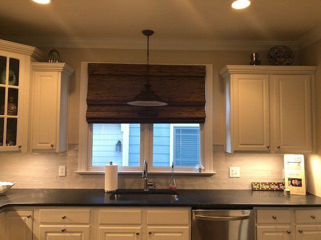 A kitchen with white cabinets and black counter tops
