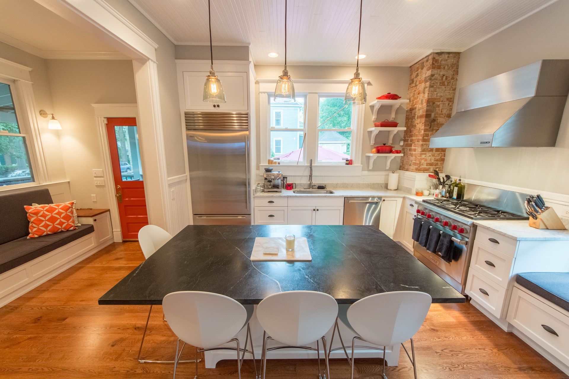 A kitchen with a large black table and white chairs.