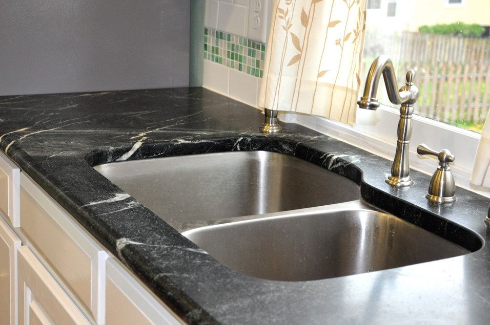 A kitchen sink with a black granite counter top