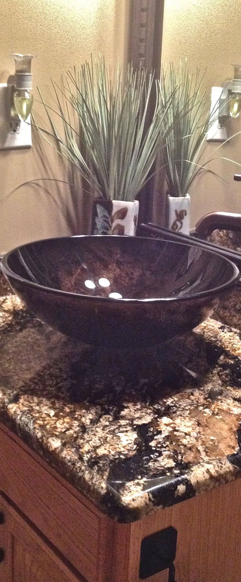 A bathroom sink is sitting on top of a granite counter top.