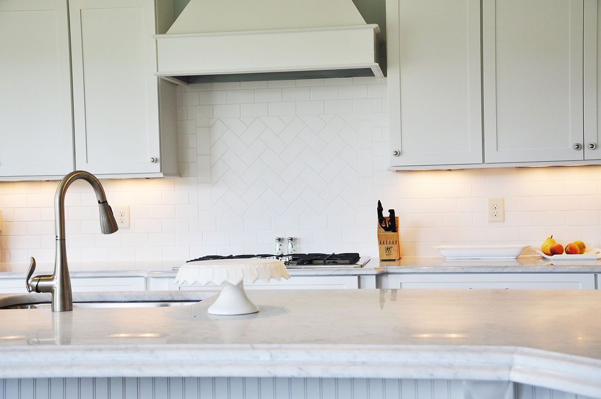 A kitchen with white cabinets , a sink , and a stove.