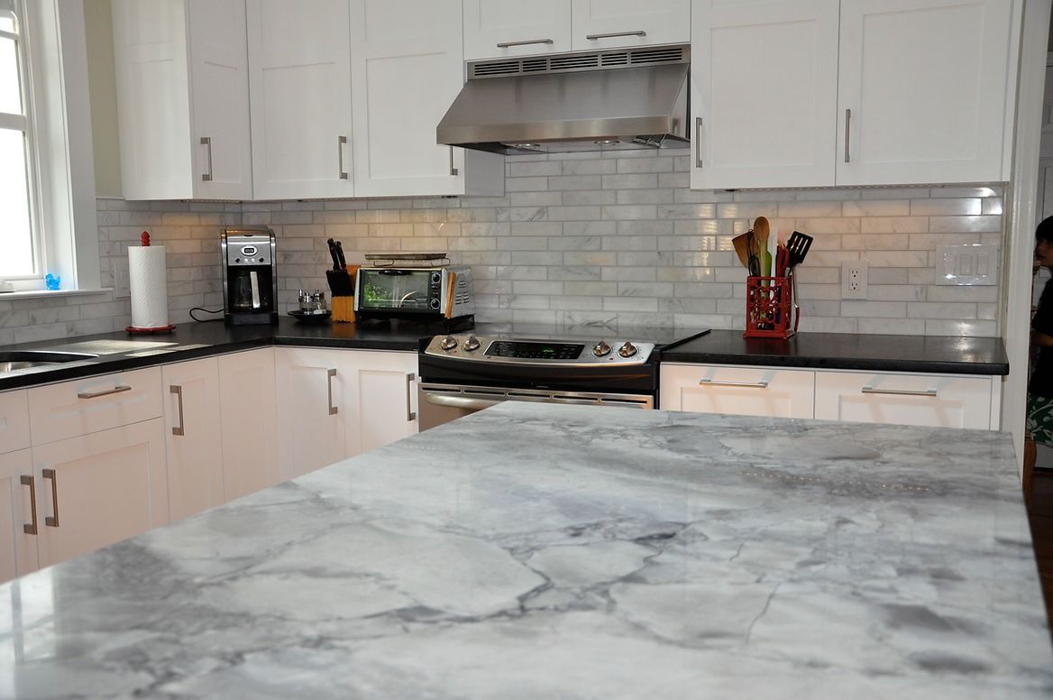 A kitchen with white cabinets and black counter tops