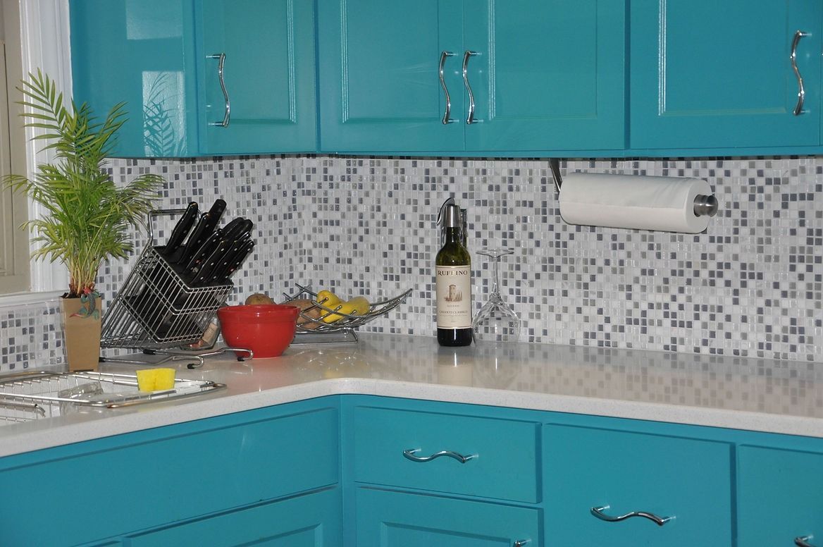 A kitchen with blue cabinets and a bottle of wine on the counter.