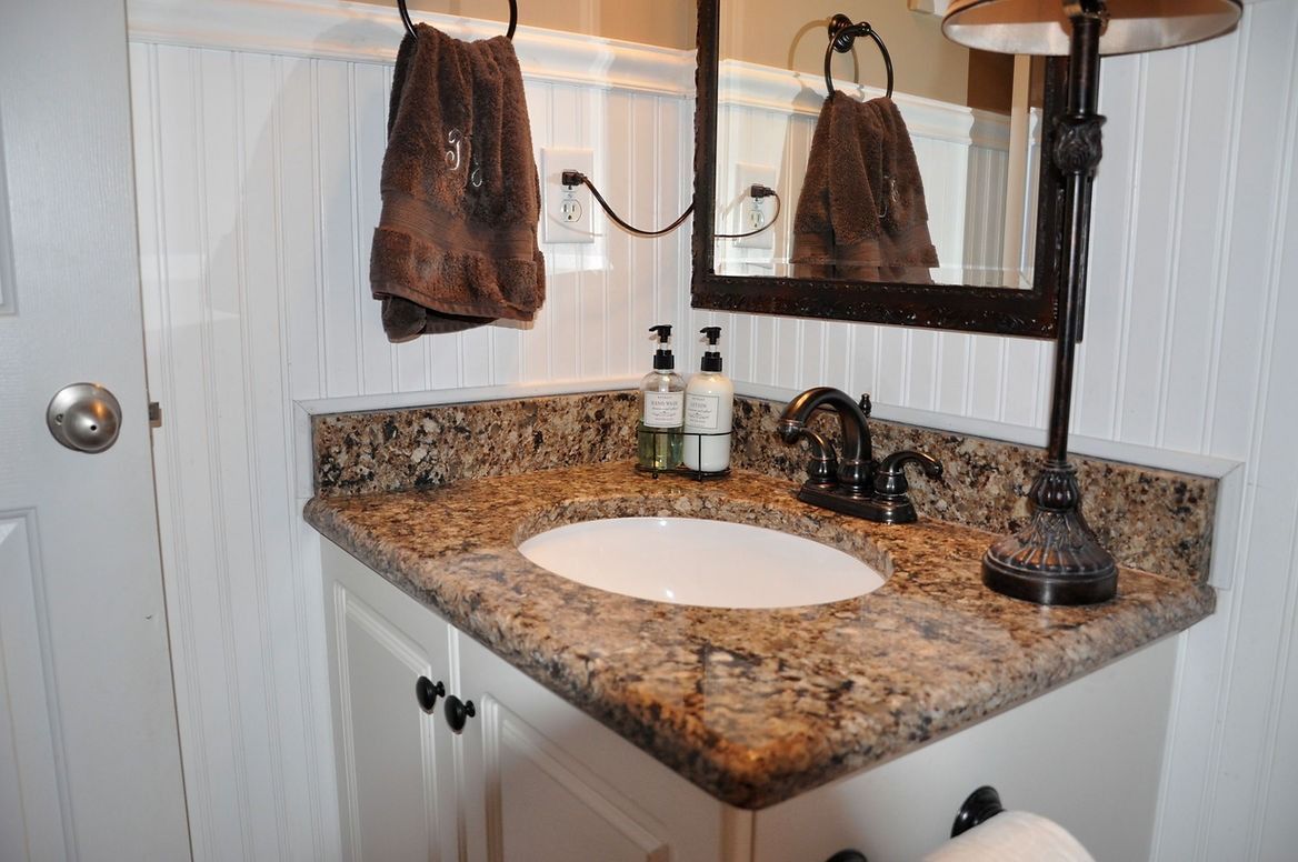 A bathroom with a sink , mirror and towels hanging on the wall.