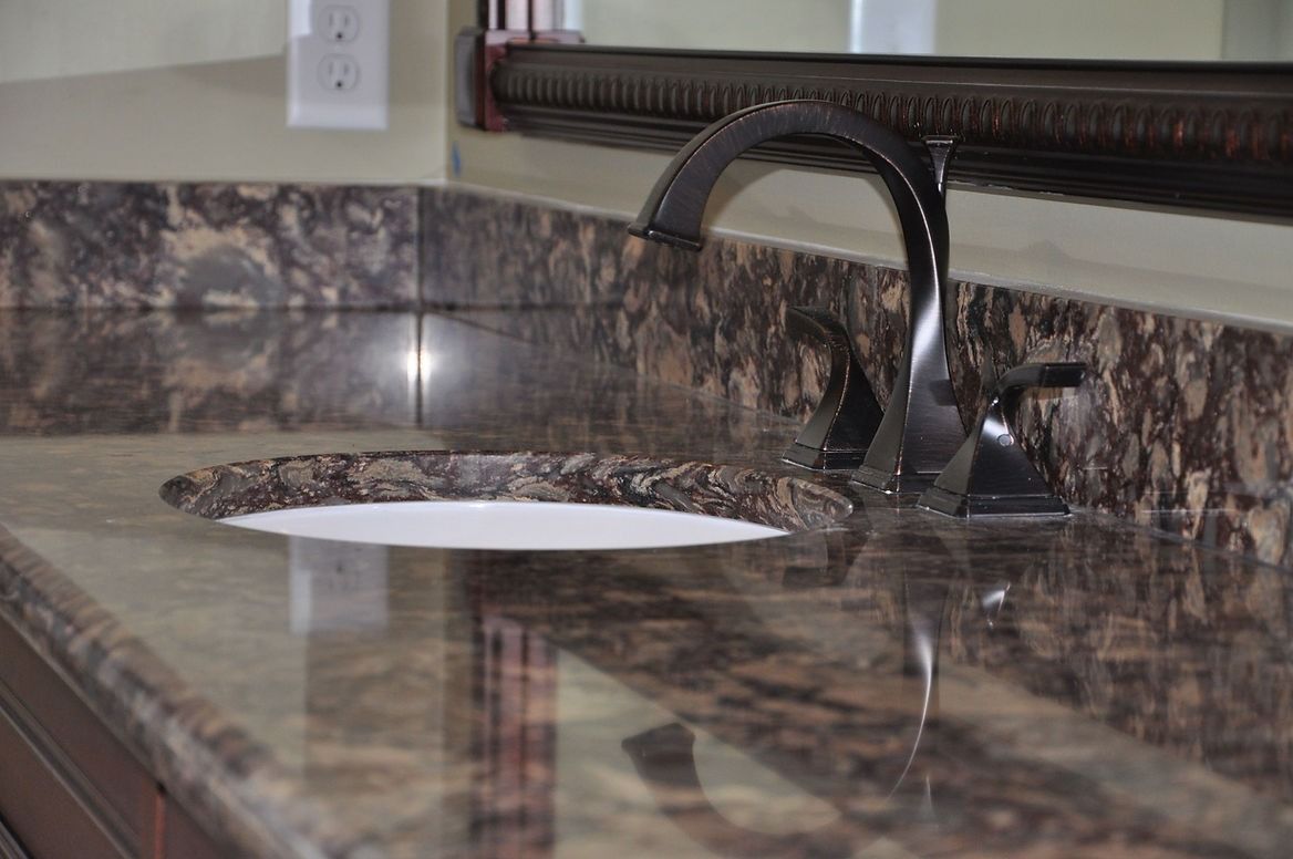 A bathroom sink with a marble counter top and a faucet.