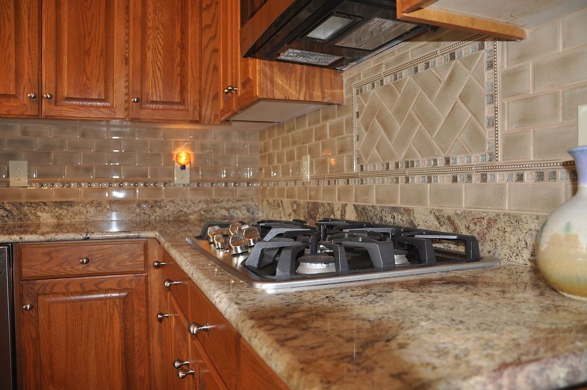 A kitchen with a stove top oven and granite counter tops