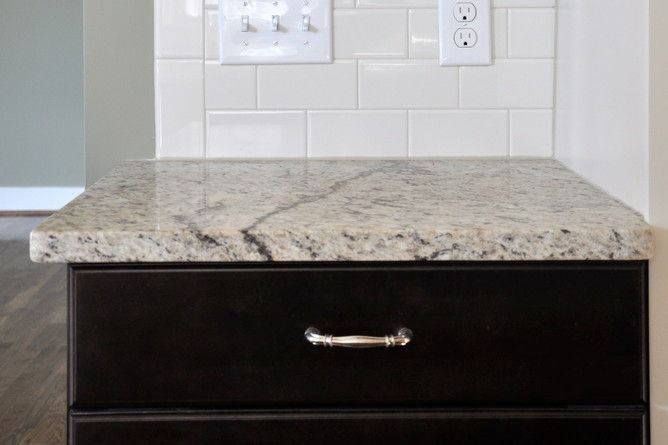 A kitchen counter with a granite counter top and a black drawer.