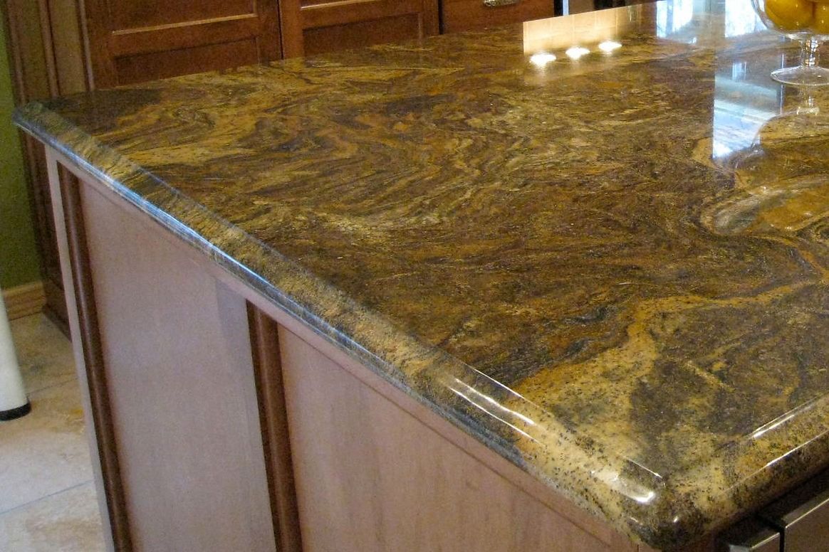 A kitchen island with a granite counter top and wooden cabinets.