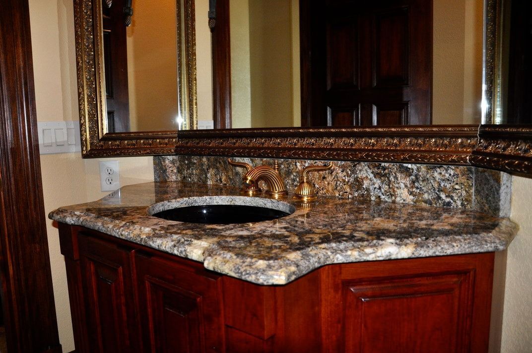 A bathroom with a sink , mirror and wooden cabinets.