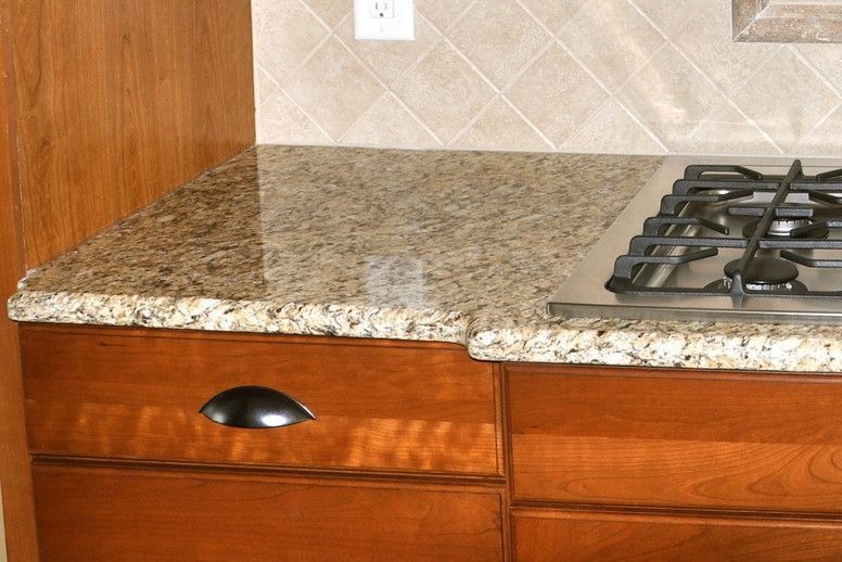 A kitchen with a stove top oven and granite counter tops