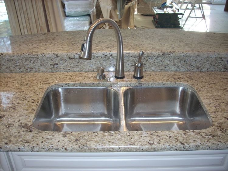 A stainless steel kitchen sink with a granite counter top