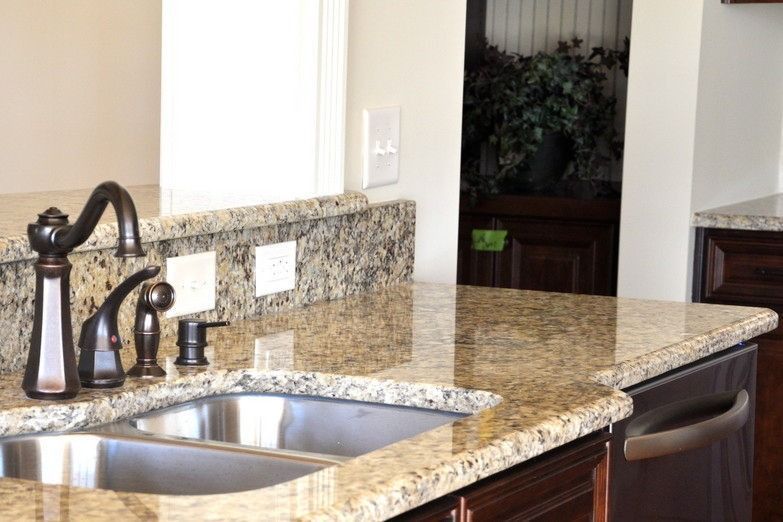 A kitchen with granite counter tops and a stainless steel sink.