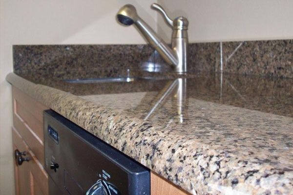 A granite counter top with a dishwasher and a sink