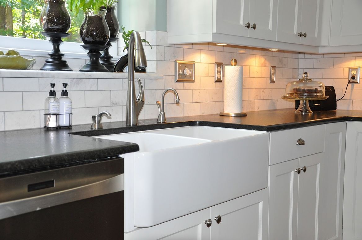 A kitchen with a white sink and black counter tops