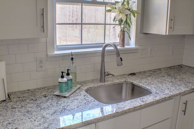 A kitchen with granite counter tops and a stainless steel sink.