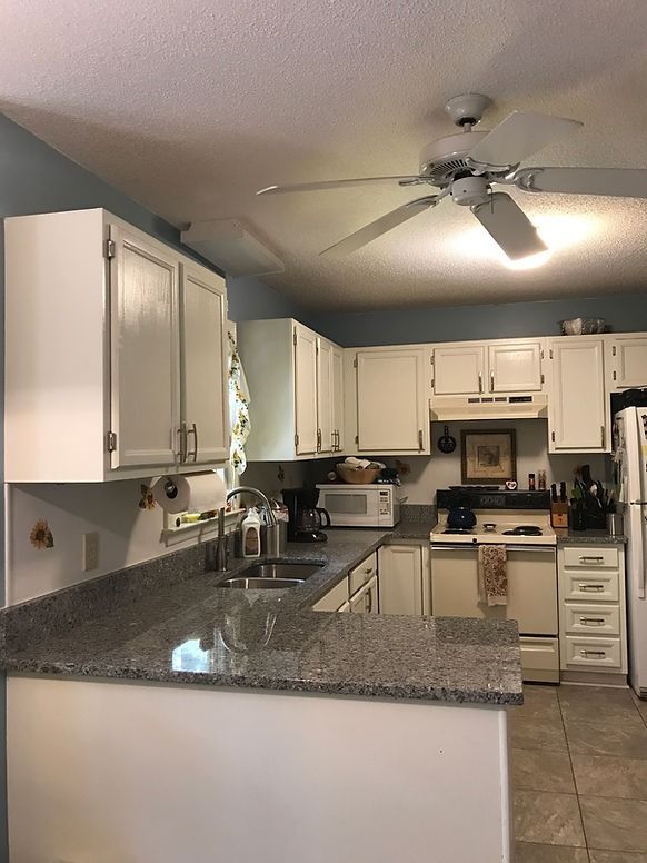 A kitchen with white cabinets and a ceiling fan
