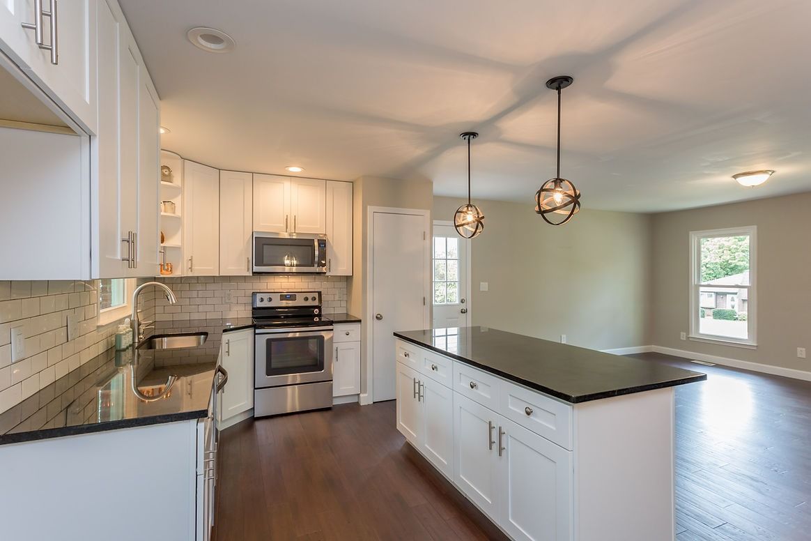 A kitchen with stainless steel appliances , granite counter tops , and white cabinets.