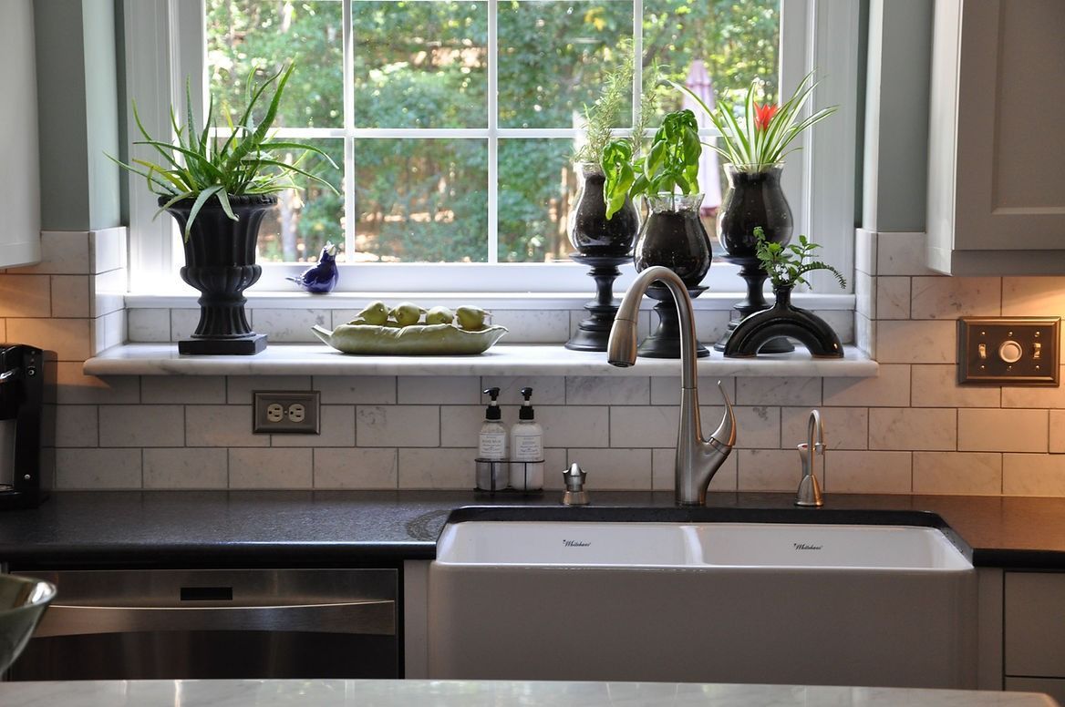 A kitchen with a sink and a window with potted plants on it.