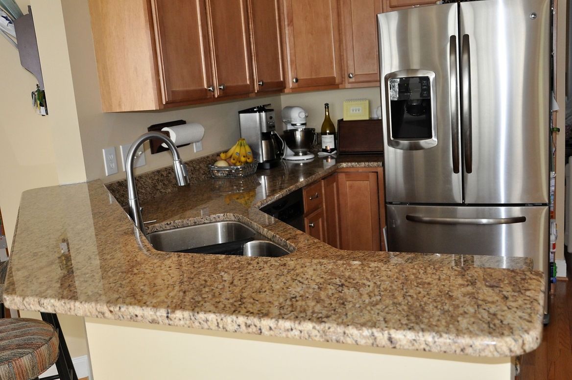A kitchen with granite counter tops and a stainless steel refrigerator