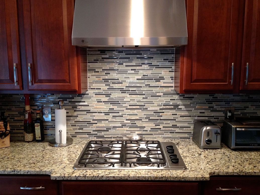 A kitchen with a stove top oven and a stainless steel hood.