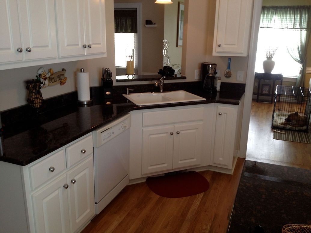 A kitchen with white cabinets and black counter tops