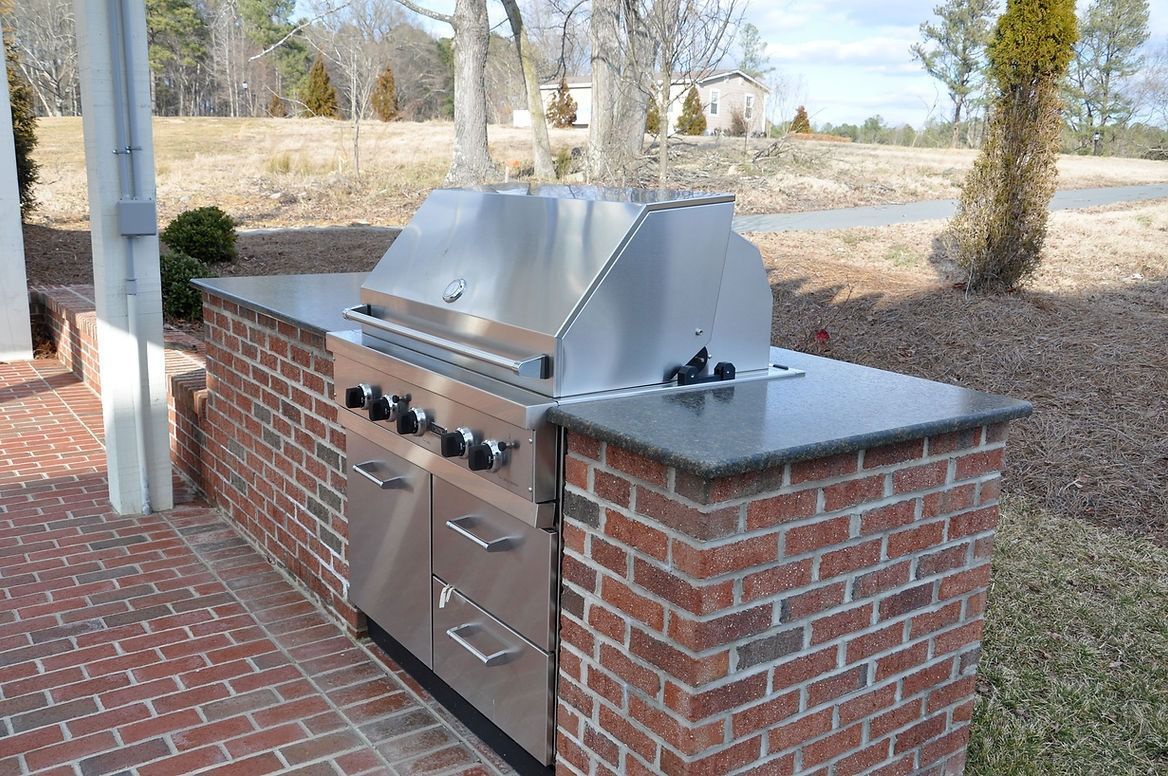 A stainless steel grill is built into a brick wall.