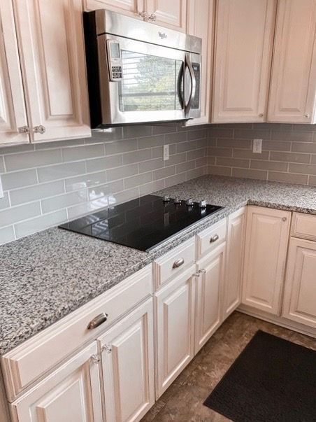 A kitchen with white cabinets , granite counter tops , a stove top oven , and a microwave.